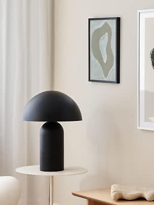 Sort bordlampe med kuppelformet skærm på hvidt sidebord i lyst, moderne rum
