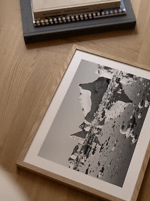 Indrammet sort-hvid fotokunst af isbjerge på egetræsgulv ved siden af en stak bøger