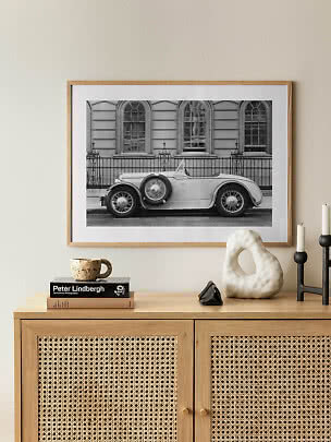 Photo noir et blanc encadrée d’un cabriolet classique au-dessus d’un meuble en bois clair