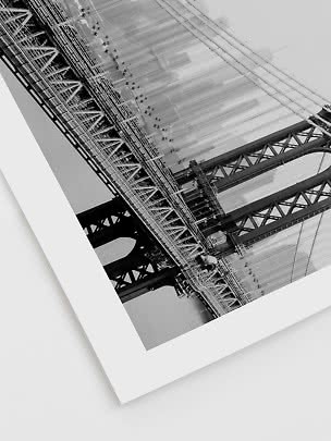Black-and-white photo of a large suspension bridge over water, viewed at an angle