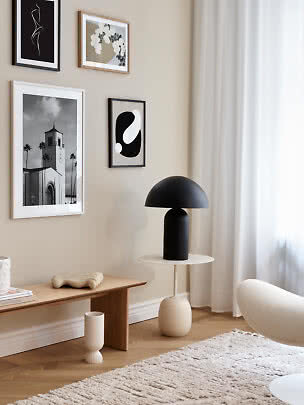 Sala moderna com parede bege, quadros, luminária preta, banco de madeira e cortinas leves