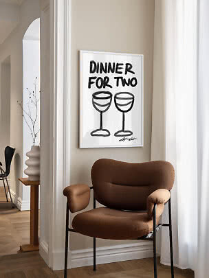 Indrammet plakat med teksten "Dinner for Two" og to vinglas over en brun lænestol