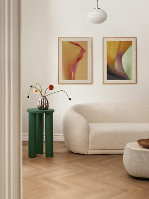 Modernes Wohnzimmer mit cremefarbenem Sofa, grünem Beistelltisch, Blumenvase und zwei Bildern