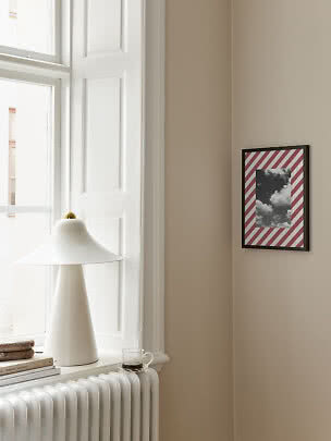 Framed print with black-and-white cloud photo and red striped border on beige wall