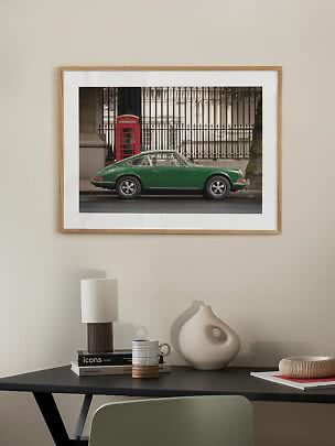 Framed photo print of a green classic car beside a red telephone box on a city street
