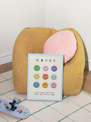 Senfgelber Sitzsack mit rosa Kissen und Smiley-Poster auf kariertem Teppich