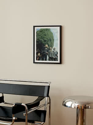 Gerahmtes Beatles-Poster an beigefarbener Wand über schwarzem Stuhl und silbernem Beistelltisch