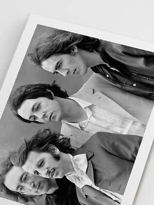 Black-and-white photo print of four people in tailored jackets and shirts with a white border.
