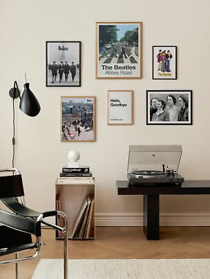 Stue med Beatles-billedvæg, pladespiller på sort bord og magasinholder med vinylplader.
