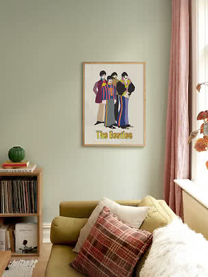 Indrammet Beatles-plakat med farverig figurillustration hænger over en grøn sofa i stuen