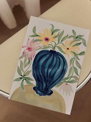 Watercolor print of a blue vase with yellow and pink flowers on white paper