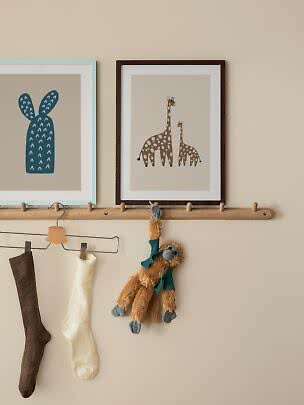 Kinderwand mit Hakenleiste, Socken, Affenplüschtier und gerahmten Hasen- und Giraffenbildern