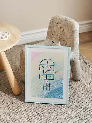 Framed hopscotch drawing with numbers, leaning against a speckled children's chair on a rug