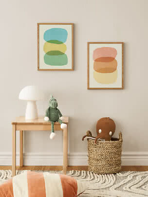 Children’s room with two abstract posters, table lamp, green doll and basket with octopus toy