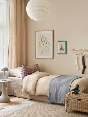 Dormitorio infantil acogedor con cama individual, lámpara de papel y banco de mimbre