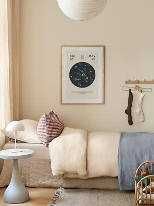 Chambre d’enfant cosy avec affiche Taureau au-dessus du lit, lampe blanche et coussins