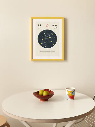 Affiche constellation Lion dans un cadre jaune au mur, au-dessus d'une table blanche avec poires et tasse