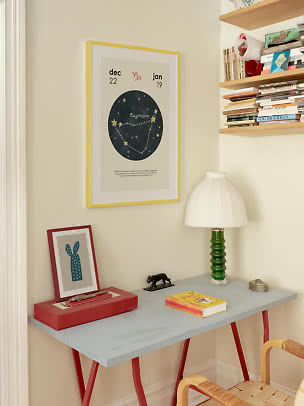 Capricorn-stjernebilledplakat i gul ramme over et lille skrivebord med grøn lampe og bøger