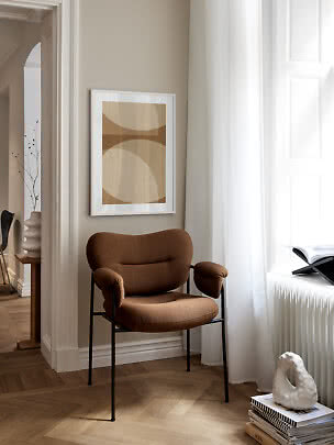 Fauteuil rembourré marron près d’une fenêtre avec affiche abstraite sur mur beige