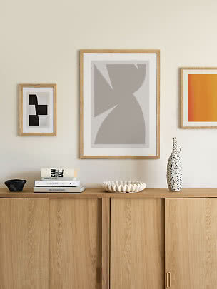 Buffet scandinave avec livres, coupe, vase à pois et affiches abstraites encadrées au mur