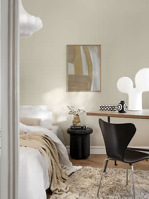 Moderne soveværelse med seng, skrivebord, sort stol, abstrakt kunst og hvid bordlampe