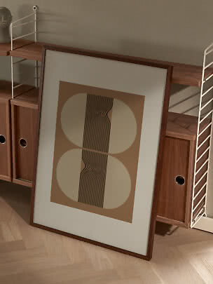 Ingelijste abstracte poster met beige vormen en zwarte golvende lijnen, leunend tegen houten rek
