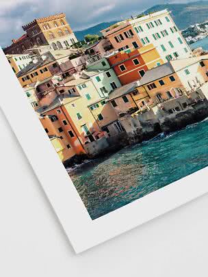 Colorful seaside houses by the water with a church on the hill under a dramatic sky