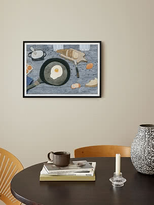Gerahmte Küchenillustration mit Spiegelei in Pfanne und Brot auf Schneidebrett über einem Tisch