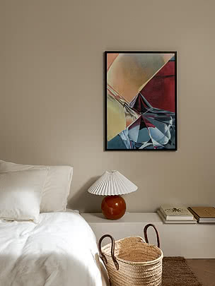 Quadro astratto incorniciato sopra un comodino bianco con lampada plissettata in camera da letto