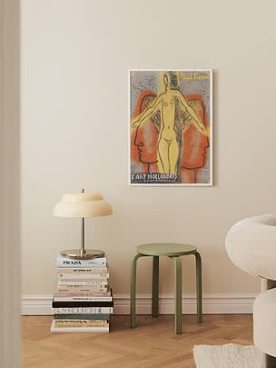 Green stool beside stacked books with table lamp and framed art poster on a beige wall