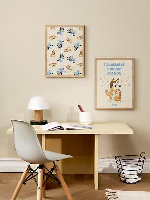 Kids desk with chair, lamp and two framed Bluey posters on a beige wall