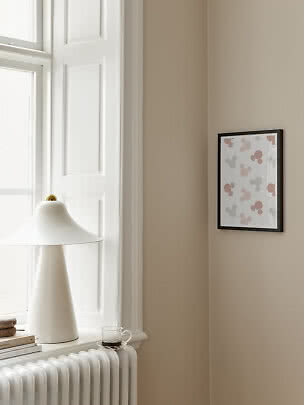 Schwarz gerahmtes Poster mit rosa und grauen Mausmotiven an beigefarbener Wand neben weißer Lampe
