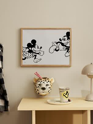 Affiche Disney noir et blanc encadrée avec Mickey et Minnie sur un mur beige au-dessus d'une table