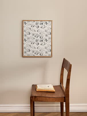 Gerahmtes Schwarz-Weiß-Poster mit Mickey-Mouse-Skizzen über einem Holzstuhl mit Büchern.