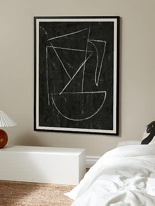 Poster astratto incorniciato con linee geometriche bianche su sfondo nero sopra un letto