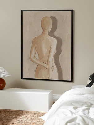 Inramad abstrakt målning av en stående figur i beige toner på en sovrumsvägg.
