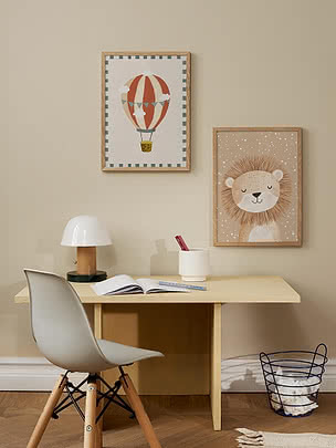 Scrivania per bambini con sedia bianca, lampada e due poster da parete con mongolfiera e leone