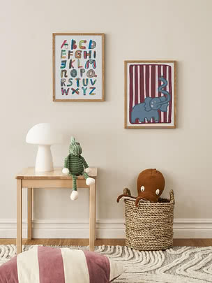 Børneværelse med alfabetplakat, elefantplakat, hvid lampe, grøn bamse og kurv med blæksprutte