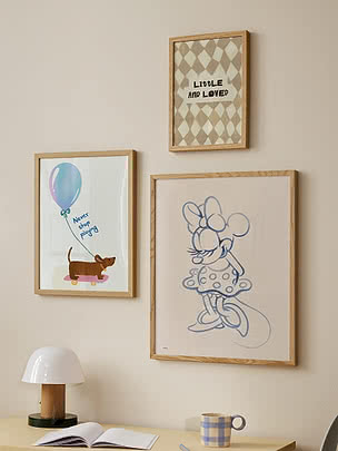 Drei gerahmte Poster an der Wand über einem Schreibtisch, mit Minnie Maus und Hund mit Ballon.
