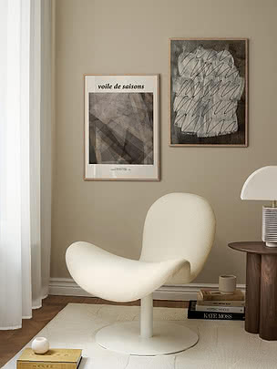 Print Voile de Saisons in eiken lijst naast een donkerdere print op een beige muur boven een crèmekleurige fauteuil
