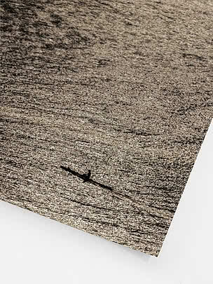 Schuine close-up van de ongelijste print met het dichte rimpelveld, de zwarte romp en het warme bijna monochrome licht