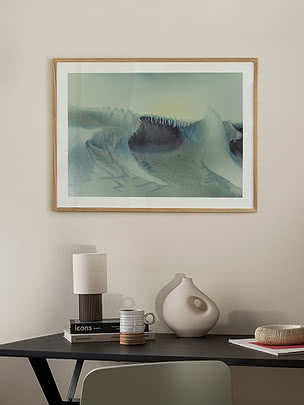 Druck Icy Dune im Eichenrahmen an beiger Wand über einem schwarzen Schreibtisch mit Lampe, blasser Vase und grünem Stuhl