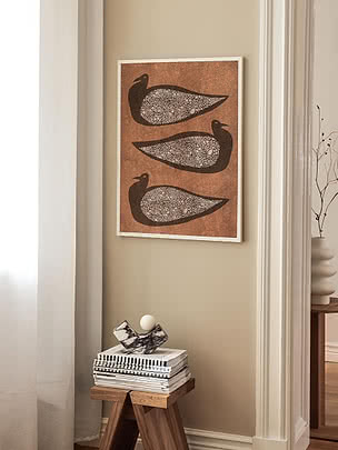 Trycket Textured Birds i vit ram på beige vägg i en smal nisch ovanför en träpall med böcker