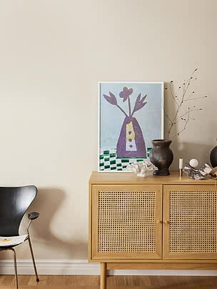 Still Life Collage print in a pale frame standing on a light oak cane sideboard with a dark vase and dried branches