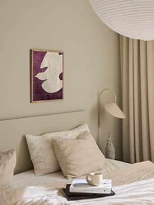 Druck Flying White Dove im Eichenrahmen an beiger Schlafzimmerwand über einem Bett mit cremefarbenen Kissen und einer Wandleuchte