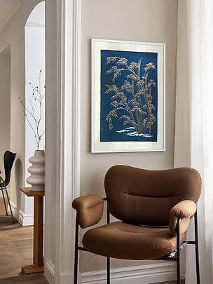 Poster Bamboo in Snow in cornice bianca su parete beige d'ingresso, sopra una poltrona bouclé marrone vicino a un arco