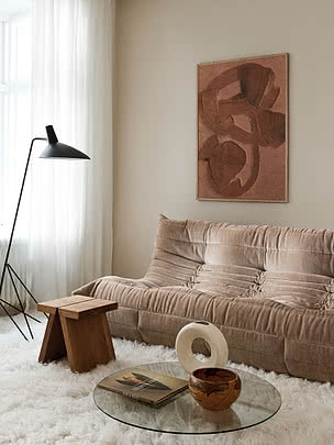 Trykket Textured Curves uindrammet på en beige væg over en modulsofa i rosa velour med en sort gulvlampe