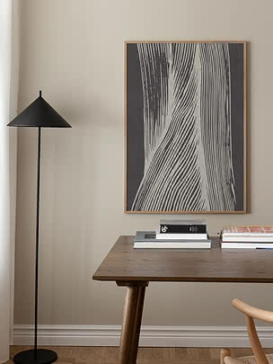 Trycket Shadow Lines i ekram på beige vägg ovanför ett mörkt träskrivbord med böcker och en svart golvlampa