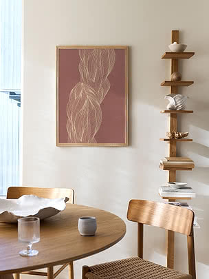 Trykket Braided Flow i egeramme på en beige væg ved siden af en hyldestige i træ over et rundt spisebord