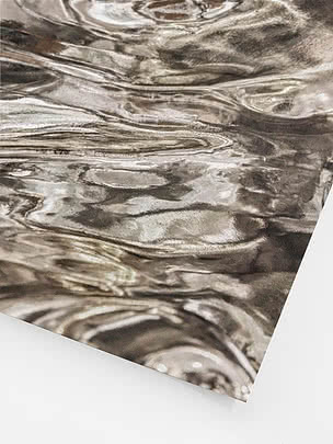 Primo piano angolato della stampa senza cornice con le pieghe riflettenti, le alte luci quasi bianche e la grana sulla superficie metallica